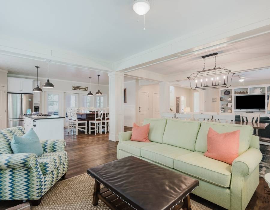 Spacious open-concept living area at 15 Flamingo Street vacation rental in Hilton Head, featuring a bright green sofa, full kitchen, large dining table, and stylish coastal decor—ideal for big groups