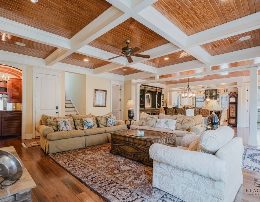 Elegant and spacious living room at 28 Pelican Street vacation rental in Hilton Head, featuring coffered wood ceilings, classic decor, and multiple seating areas perfect for big groups and family gatherings