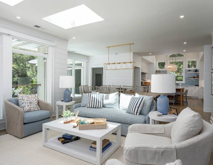 Bright coastal living room at 45 S Sea Pines Drive vacation rental in Hilton Head, featuring open layout, stylish white and blue decor, skylights, and a spacious kitchen—perfect for large groups and families