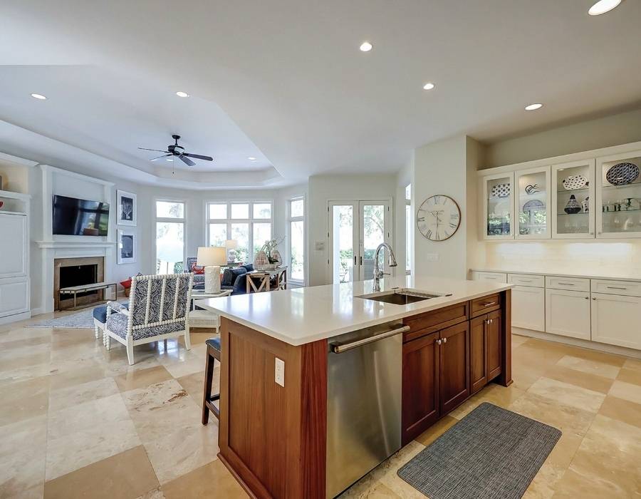 Elegant open-concept kitchen and living room at 49 Mooring Buoy vacation rental in Hilton Head, featuring a large island with seating, cozy fireplace, and abundant natural light—ideal for big group stays